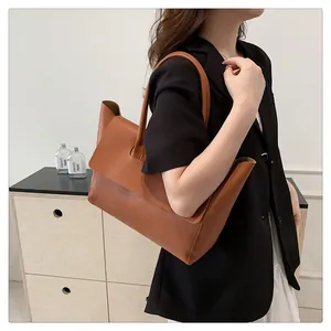 Detailed view of camel leather tote bag carried by model in a black blazer suit