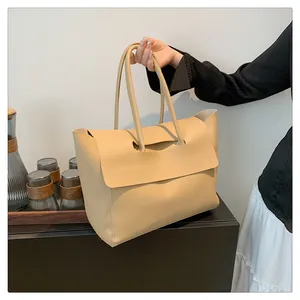 Close-up of beige minimalist tote bag with unique cutout flap closure and smooth leather finish