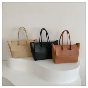 Three minimalist large capacity tote bags in beige, black, and brown on a white display