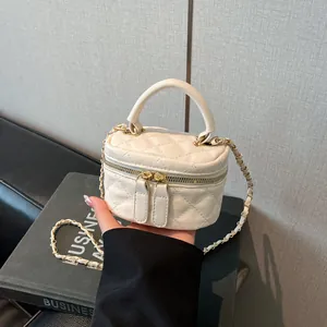 White quilted mini box crossbody bag with gold chain strap on a business book background