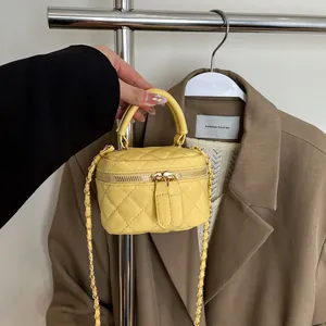 Yellow quilted mini box crossbody bag with chain strap and gold hardware shown on a suit
