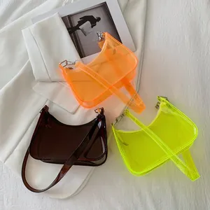 Close-up of transparent PVC underarm bags in orange, green, and brown with metal buckles