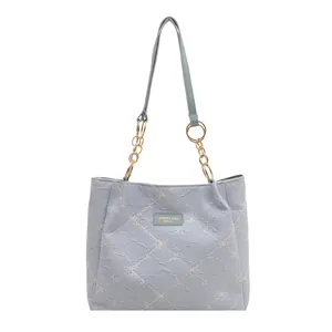 Light blue embroidered canvas tote bag with floral patterns and gold chain shoulder strap