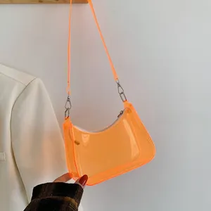 Detail of the vibrant orange transparent crescent bag with its sleek jelly texture and silver hardware