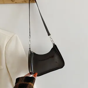 Detail of black glossy crescent shoulder bag with silver hardware and sleek zip closure