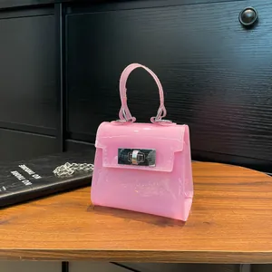 Mini bolso rosa de PVC estilo Kelly con cadena plateada sobre mesa de madera
