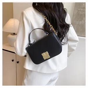 Detail van minimalistische zwarte leren crossbodytas met gouden ketting en gesp