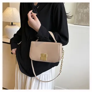 Detail van beige crossbodytas met gouden gesp en leren schouderriem met ketting