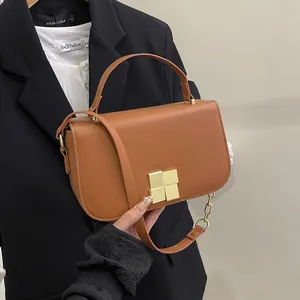 Bruine PU-lederen schoudertas met gouden gesp en ketting gedragen door een model