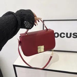 Stijlvolle rode kunstlederen crossbodytas met gouden ketting gedragen door model