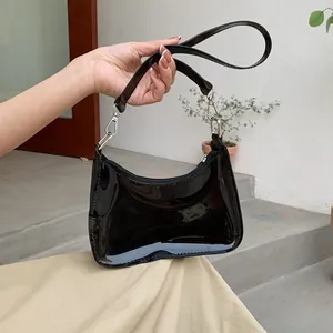 Close-up of black patent leather crescent shoulder bag with silver metallic hardware detail