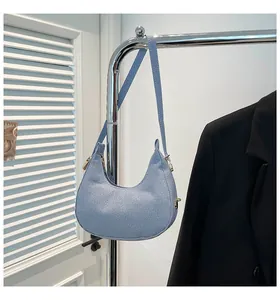 Detail of light blue crescent bag showing twill texture and gold metal zipper hardware