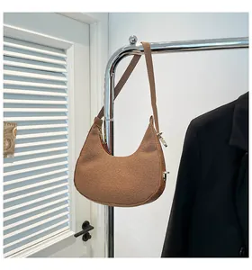 Close-up of brown woven hobo shoulder bag with golden zipper on metal hanger