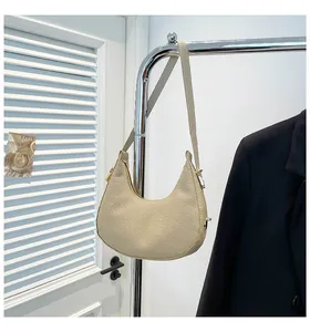 Detail of light beige crescent hobo bag with twill texture and gold-tone metal zipper