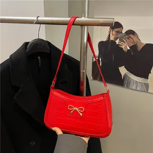 Rote Unterarmtasche mit Krokodilmuster und goldener Schleife für einen Vintage-Look