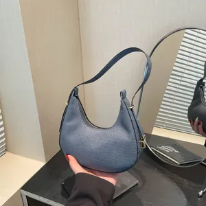 Minimalist navy blue woven crescent shoulder bag with golden hardware and adjustable strap