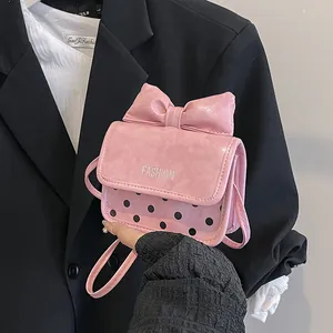 Petit sac carré rose à pois avec grand nœud porté à la main pour femmes