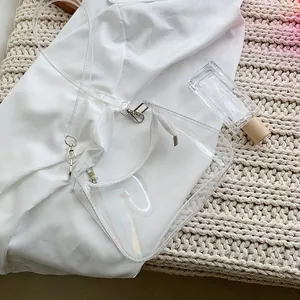 Close-up of transparent PVC shoulder bag with white fabric liner and silver metal hardware