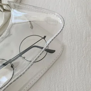 Detail shot of clear PVC bag showing white stitching, metal buckle and transparent texture