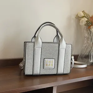 Sac fourre-tout carré argenté élégant avec texture métallique et logo THE BAG