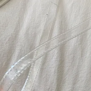 Macro view of transparent PVC shoulder strap featuring detailed white stitching details
