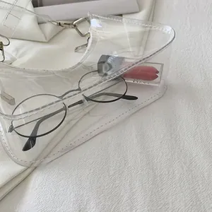 Detail of transparent PVC shoulder bag with white piping and silver metal buckle hardware