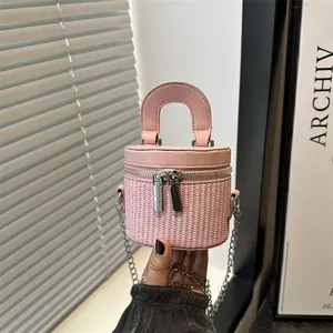 Bolso cubo cilíndrico rosa con base de ratán trenzado y doble cremallera de piel con cadena