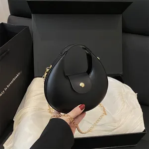 Minimale zwarte leren halve maan tas met goudkleurige details en kettingriem