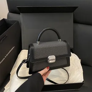 Grijze geweven crossbodytas met zwarte bies en zilveren draaislot in een luxe geschenkdoos