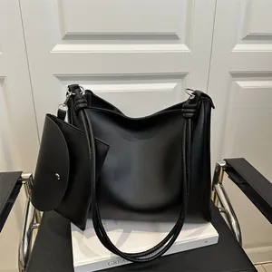 Minimalist black leather tote bag with knotted shoulder strap and matching coin purse