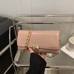 Roze schoudertas met krokodillenreliëf en gouden ketting in een moderne setting