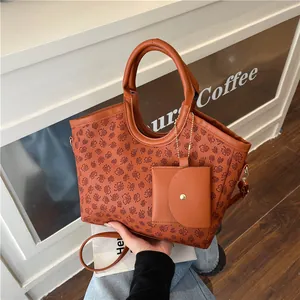 Brown tote bag with floral print and matching small pouch on a stylish gold chain