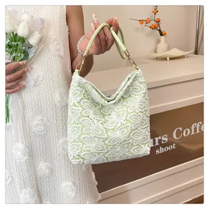 Detail of light green bucket bag with white floral lace overlay and gold hardware