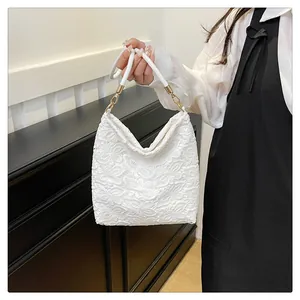 Detail of white lace crochet shoulder bag with gold metal buckle and leather strap