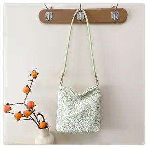 Close-up of light green lace tote bag with butterfly patterns hanging on a wooden hook