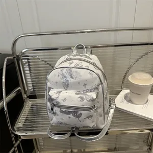 Chic white backpack with silver butterfly prints and stars on a modern display shelf