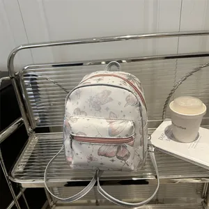 Mini PU backpack featuring pink butterfly prints and silver star patterns on white leather
