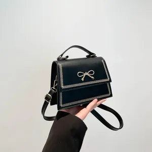 Bolso bandolera negro chic con lazo metálico y elegantes costuras de contraste beige