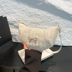 Cream woven crescent crossbody bag with golden bow and leather strap for women