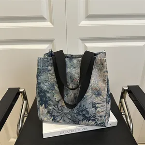 Borsa tote in jacquard floreale blu con manici neri esposta su un libro decorativo