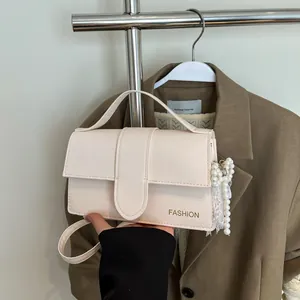 Sac bandoulière élégant en cuir crème avec pompon en perles et lettrage doré chic