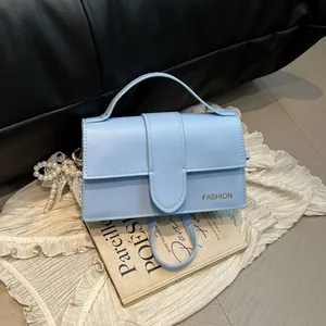 Petit sac à main bleu clair en simili cuir avec charm en perles sur tissu blanc plissé