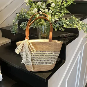 Minimalist woven straw bucket bag with brown leather handles and lace bow decoration