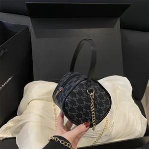 Mini sac cylindrique noir avec motif M bleu et bandoulière en chaîne dorée chic