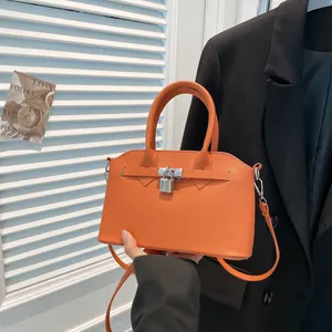 Chique oranje schelptas van leer met lychee-structuur en metalen slotversiering