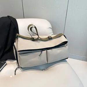 Large beige nylon travel bag with olive straps on a white chair for gym and business