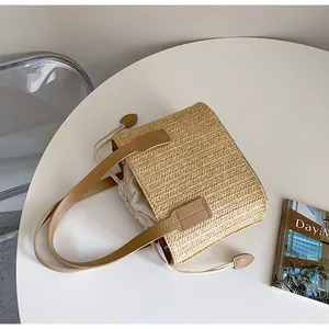 Top view of beige straw woven tote bag with brown leather handles and drawstring liner