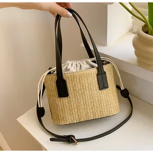 Close-up of V-shaped straw weave detail with black leather handle and drawstring liner