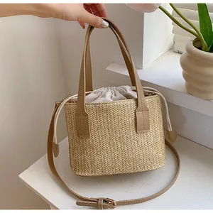 Close-up of woven straw bucket bag with brown leather straps and drawstring liner