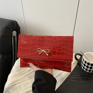 Elegant red crocodile texture handbag with golden bow buckle in minimalist setting
